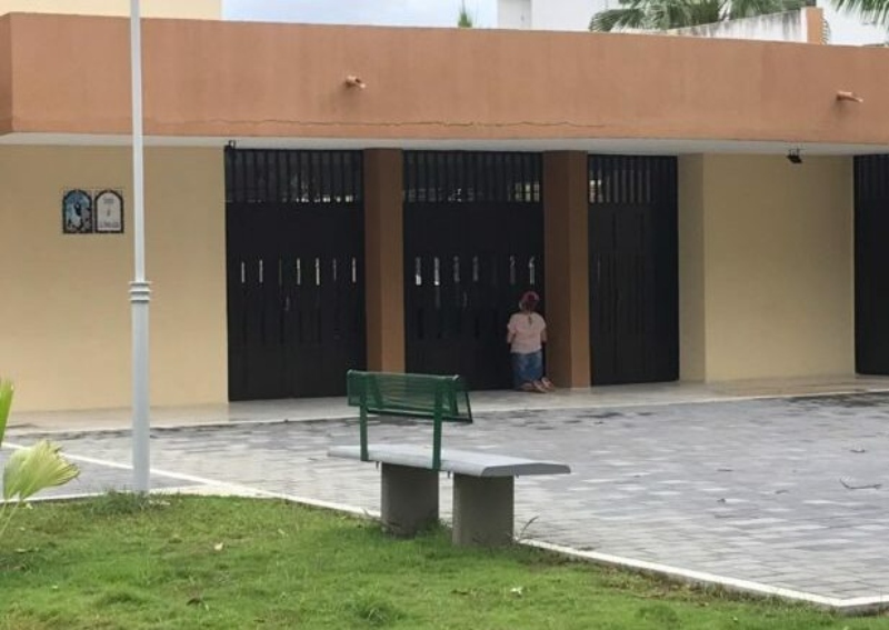 Fe sin límites: mujer ora en  puerta de iglesia cerrada